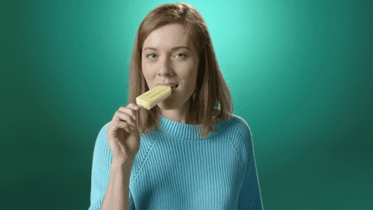 Frau ist ein gelbes Capri Eis und lächelt