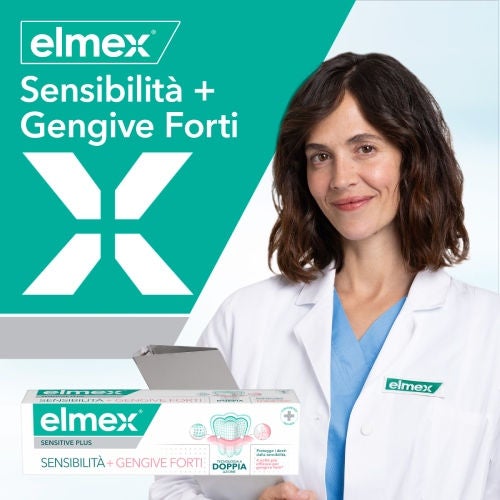 Una dottoressa in camice bianco tiene in mano una confezione di dentifricio Elmex "Sensibilità + Gengive Forti Sbiancante Delicato", su uno sfondo bianco e verde con il logo del brand